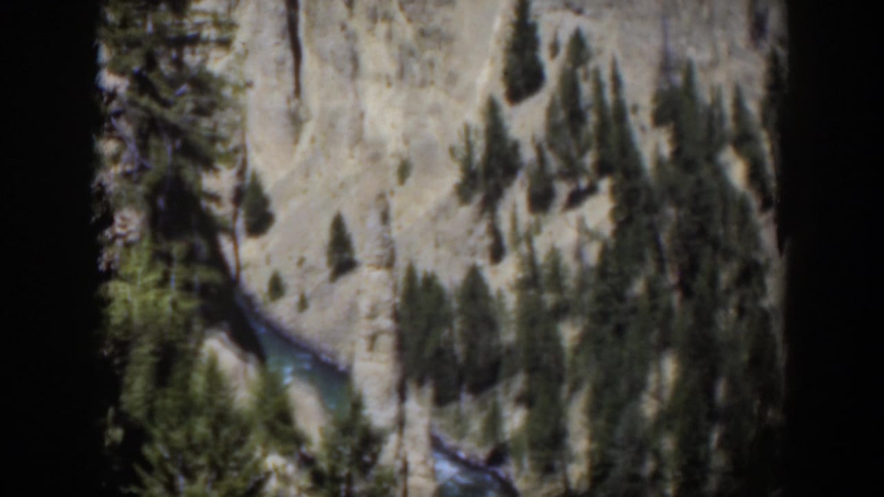 1951 Wyoming 8mm frame looking down on a river channel between pale rock and dark pine clusters.