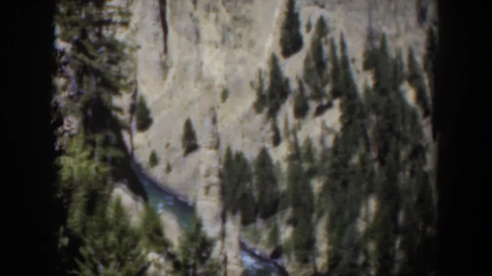 1951 Wyoming 8mm frame looking down on a river channel between pale rock and dark pine clusters.
