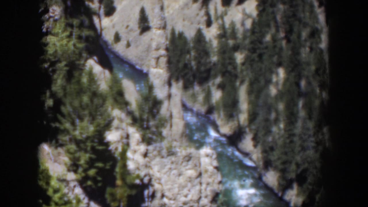 1951 Wyoming 8mm frame with visible rapids coursing through a rocky canyon bordered by pine trees.