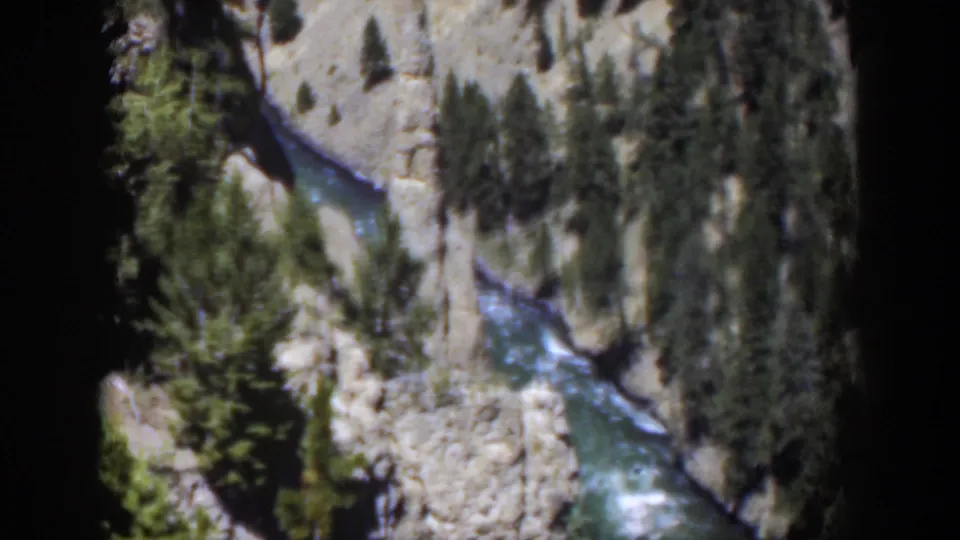 1951 Wyoming 8mm frame with visible rapids coursing through a rocky canyon bordered by pine trees.