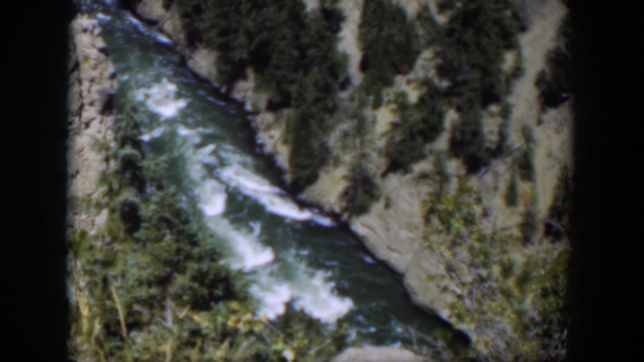 1951 Wyoming 8mm still of whitewater running through a narrow rocky canyon with brush along the banks.
