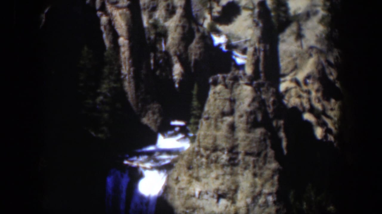 1951 Wyoming 8mm frame with foaming white water, steep tan rock, and deep shadow around the canyon.