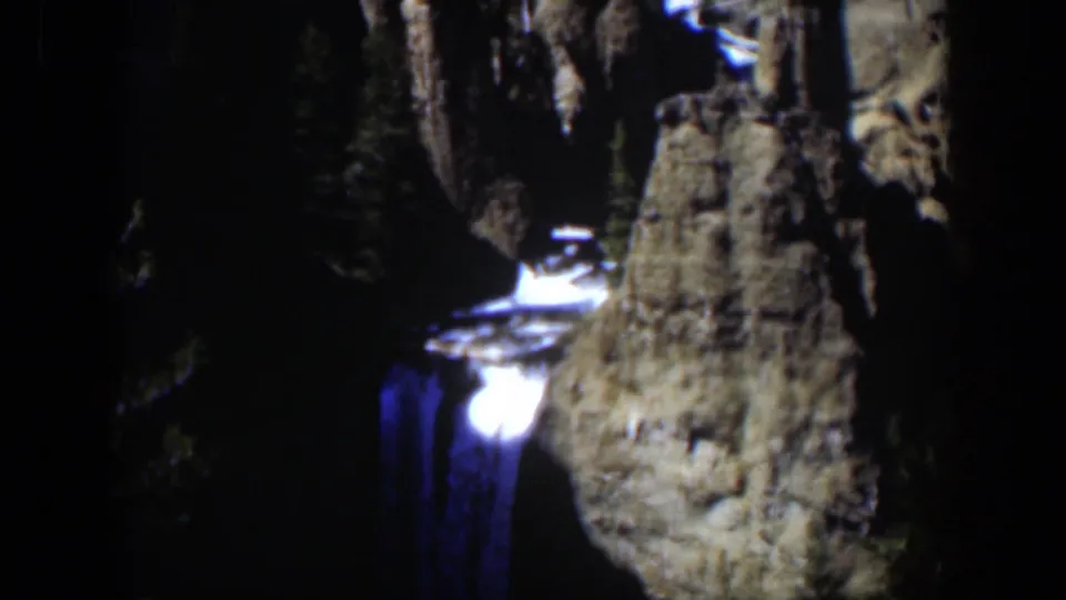 1951 Wyoming 8mm frame showing an artificially lit waterfall dropping through a dark rocky canyon.
