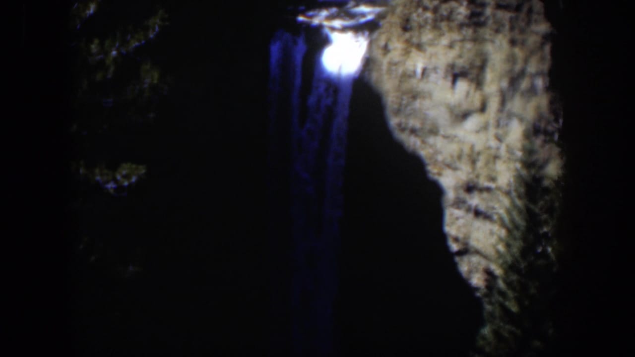 Waterfall and bright upper light area framed by dark rock.