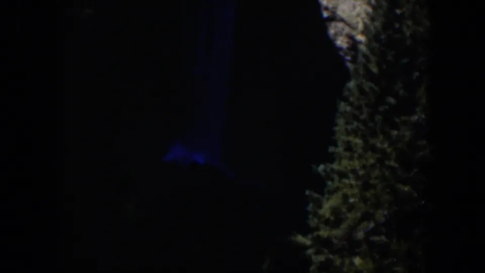 1951 Wyoming 8mm frame showing a nearly black outdoor view, blue illumination, and a rough vertical natural surface.