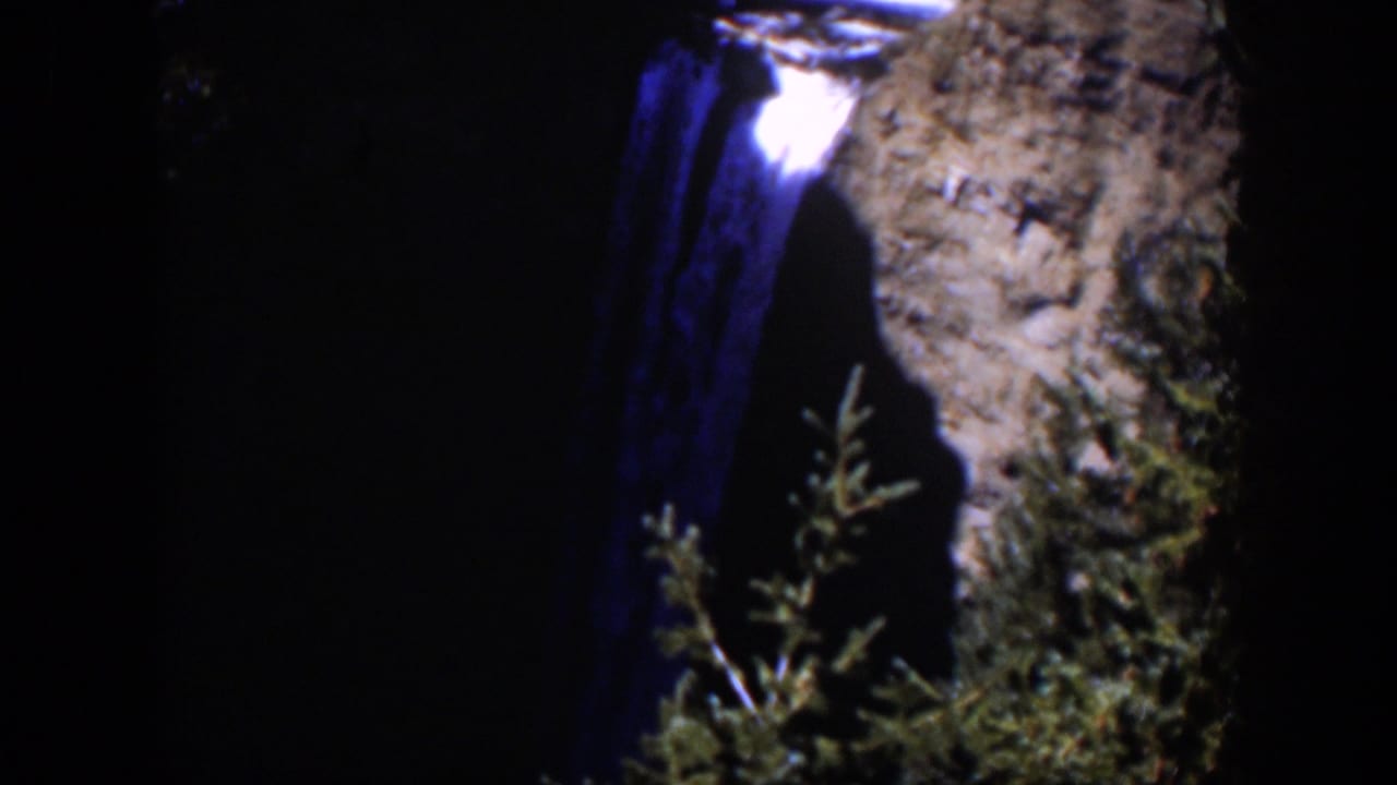 The final 1951 Wyoming frame shows blue-toned falling water, a cliff face, and shadowed evergreen growth.