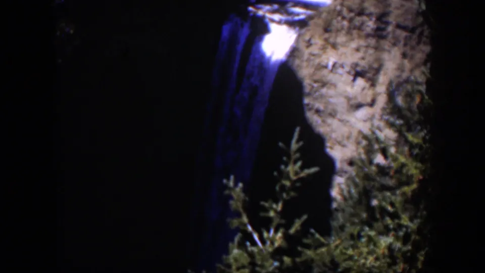 The final 1951 Wyoming frame shows blue-toned falling water, a cliff face, and shadowed evergreen growth.