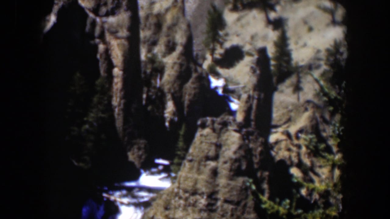 1951 Wyoming color 8mm frame with a waterfall, rock ledges, and dense shadow in a canyon-like setting.