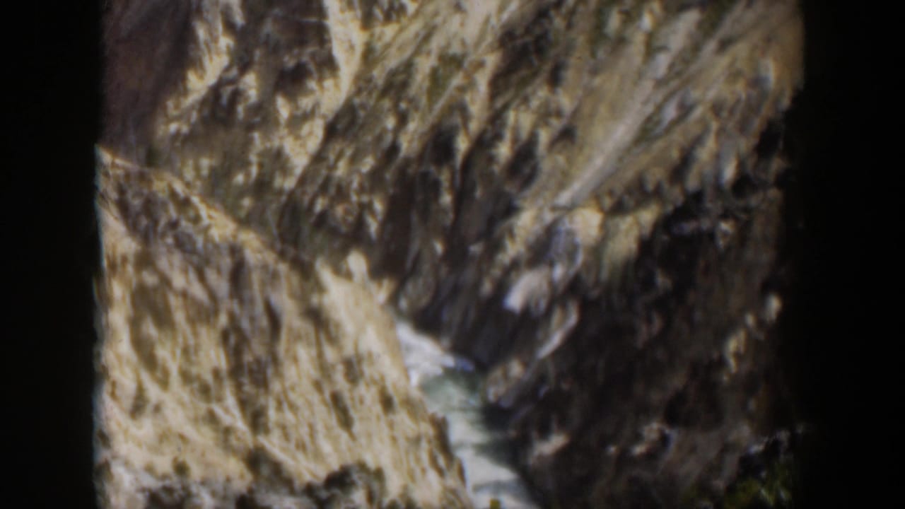 Final 1951 Wyoming 8mm frame holds on the rocky canyon and stream, with visible vignetting and soft faded color.