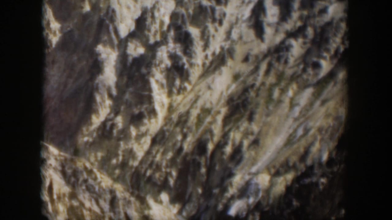 1951 Wyoming 8mm view of a rugged valley, steep eroded rock, and a faint stream below.
