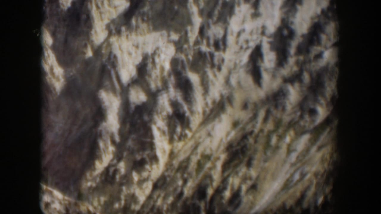 1951 Wyoming 8mm frame showing rough mountain rock textures and landslide-like pale slopes.
