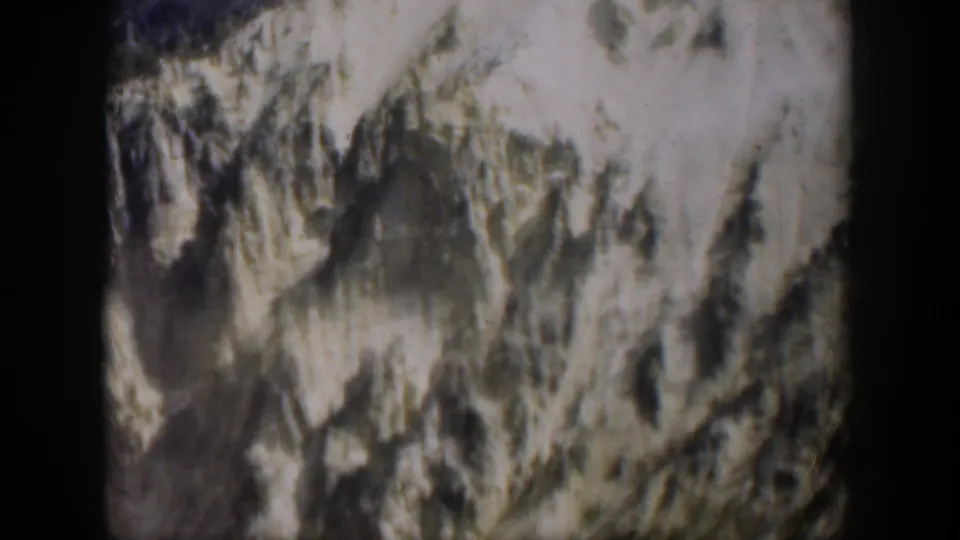 1951 Wyoming 8mm frame showing a rugged slope with pale high areas and dark striated rock.