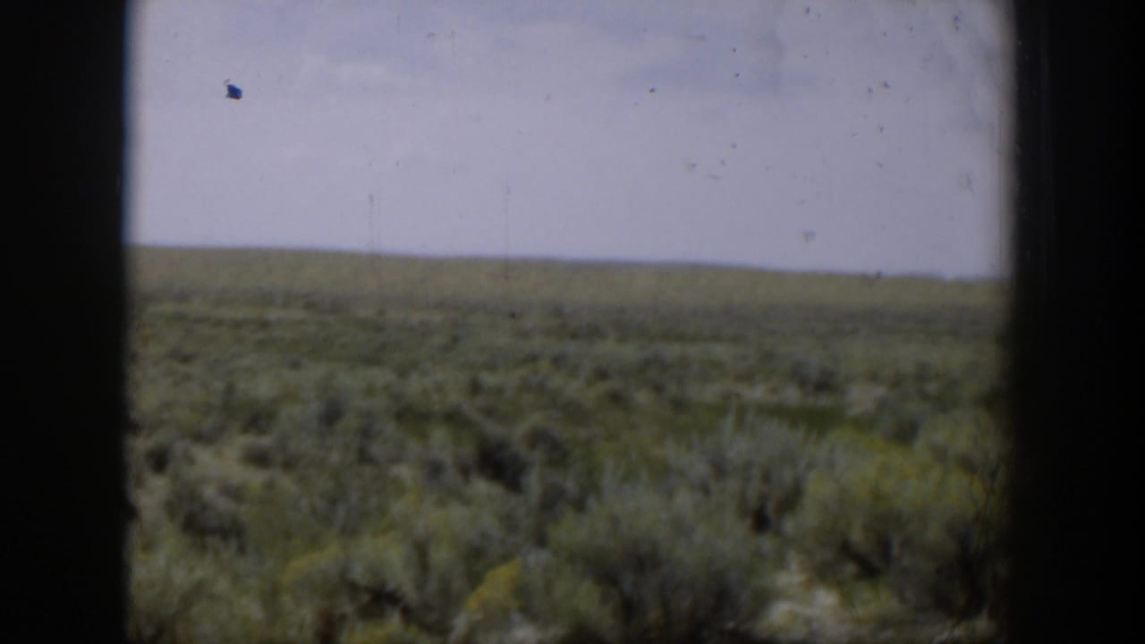 1951 Wyoming 8mm view across an open sagebrush plain, with a low horizon and pale blue sky.