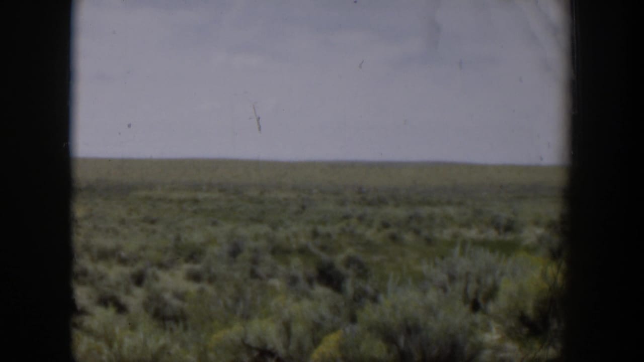 Wyoming desert plain in 1951 home-movie footage, seen past a dark central window divider.