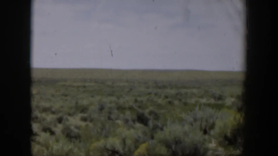 Wyoming desert plain in 1951 home-movie footage, seen past a dark central window divider.