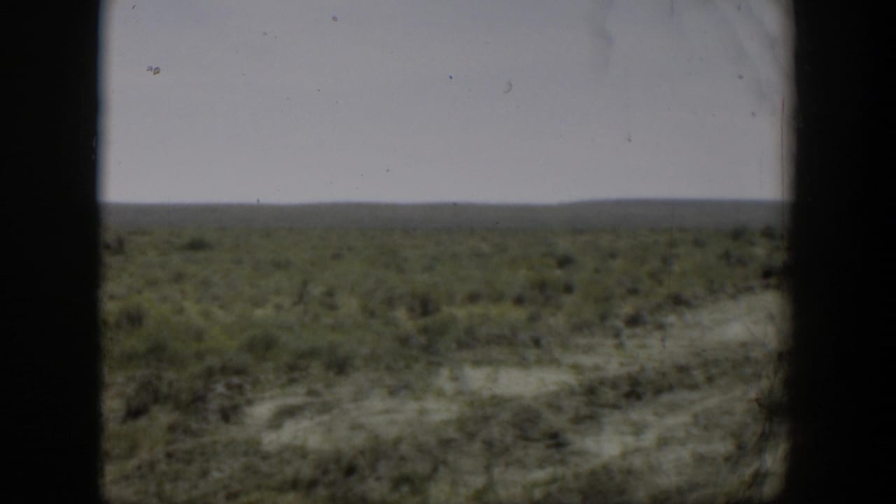 Final 1951 Wyoming landscape frame showing flat open land and sparse green growth, with any person too distant to identify in this still.