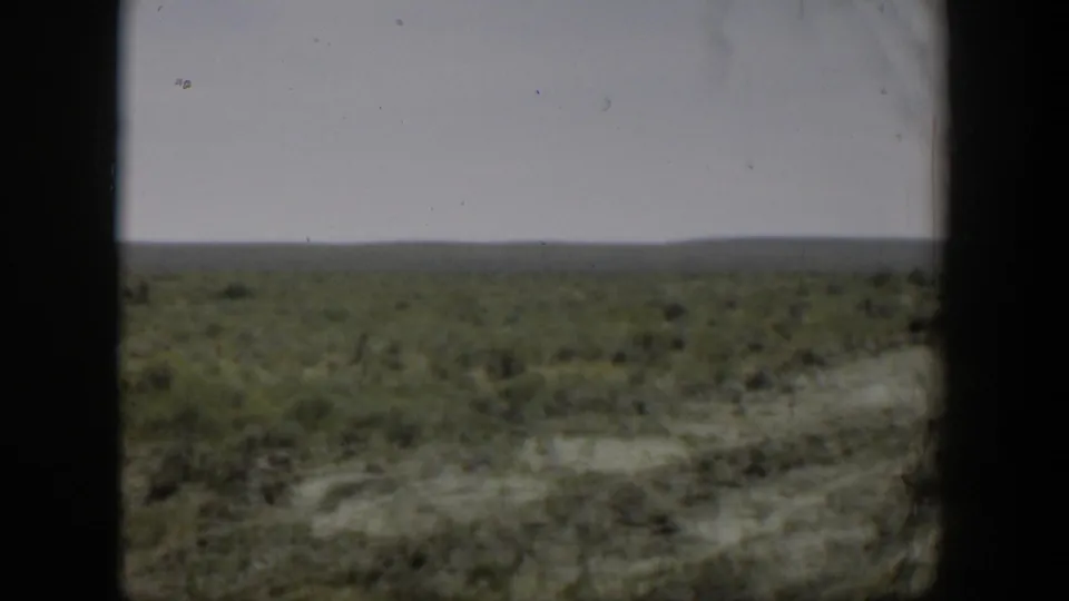 Final 1951 Wyoming landscape frame showing flat open land and sparse green growth, with any person too distant to identify in this still.