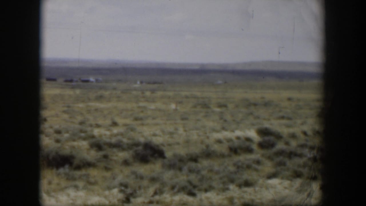 1951 Wyoming 8mm frame showing a distant deer crossing open sagebrush country under an overcast sky.