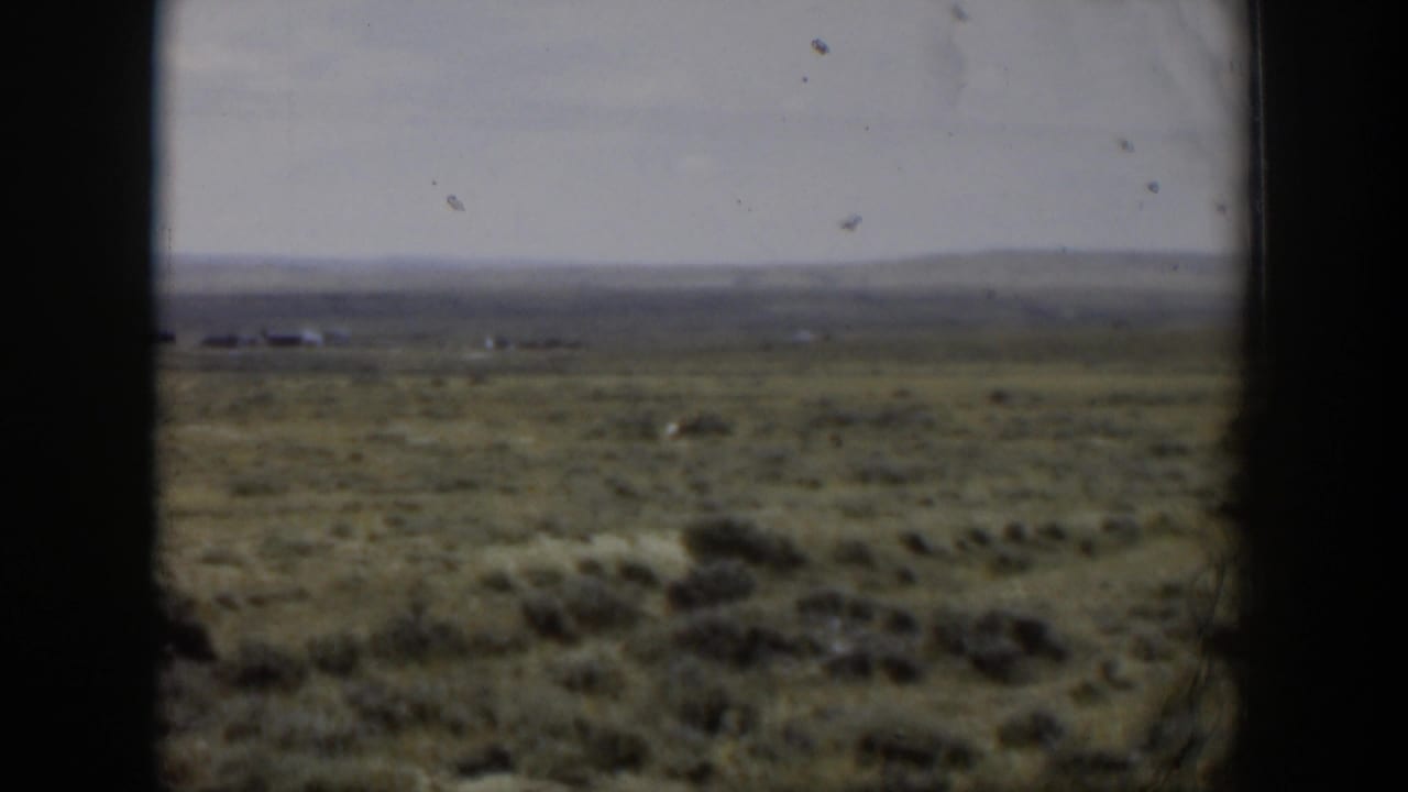 1951 Wyoming home-movie still with open rangeland, distant horizon, and a small deer moving through sagebrush.