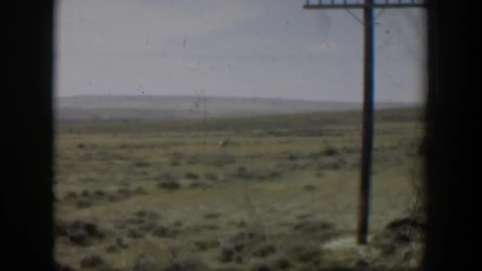 Final 1951 Wyoming frame with sparse prairie, a distant antelope, pale sky, and telephone pole along the right side.