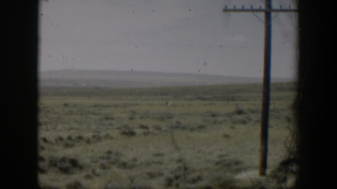 Open plain with sagebrush and a wooden utility pole seen through dark frame edges.