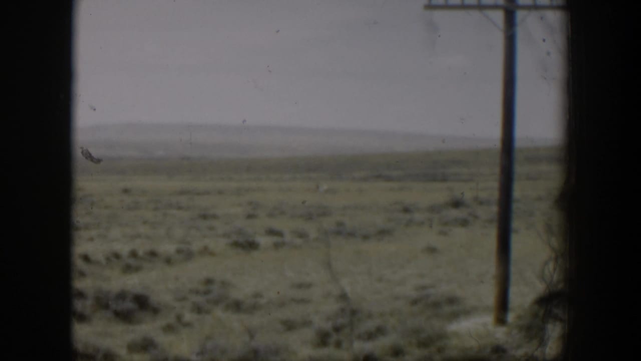 Flat rural landscape with a utility pole near the foreground and dark vertical framing.