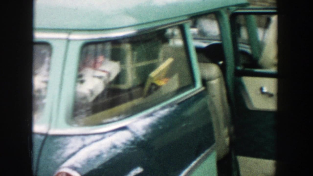 Rear side of a green station wagon with the door open and belongings inside.