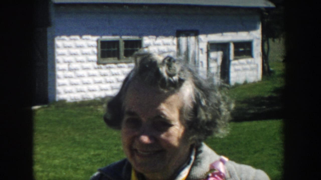 Smiling woman faces the camera with a white shed behind her.