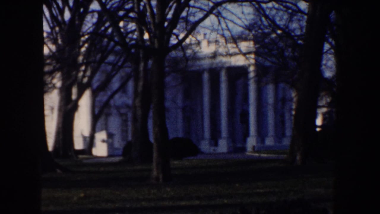 White House columns and lawn are visible through shaded tree trunks in this 1960 Washington, DC 8mm frame.