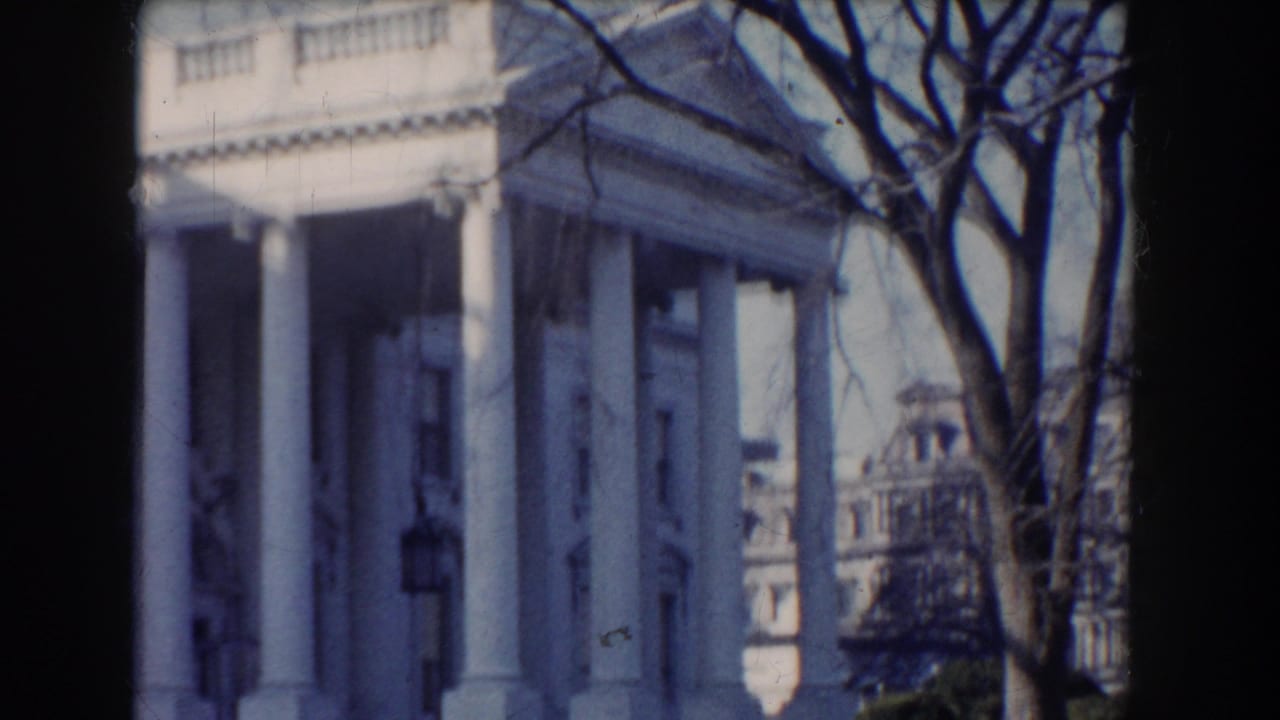 White House exterior framed by bare tree branches and dark film borders.