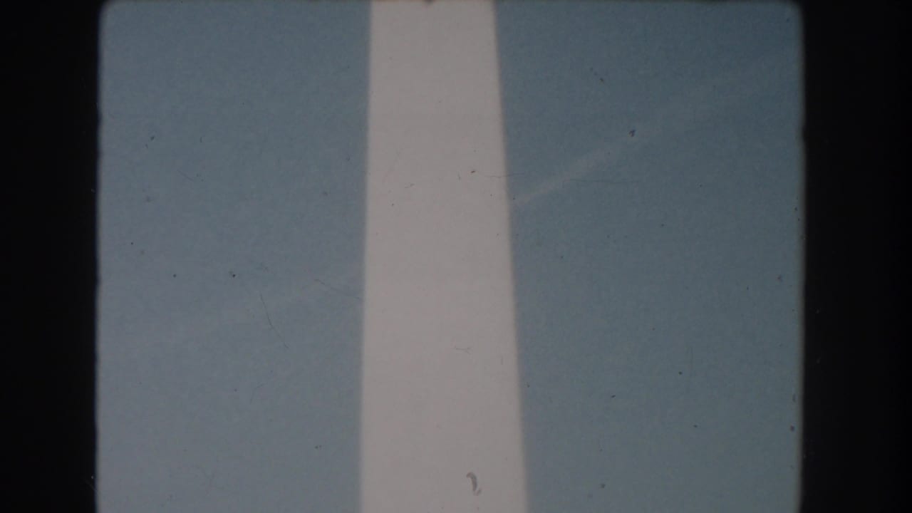 Close view of the Washington Monument shaft against pale blue sky.