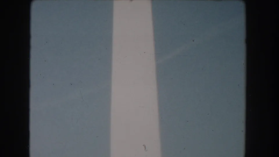 1960 Washington DC home-movie frame showing a tight, soft-focus view of the Washington Monument rising into blue sky.