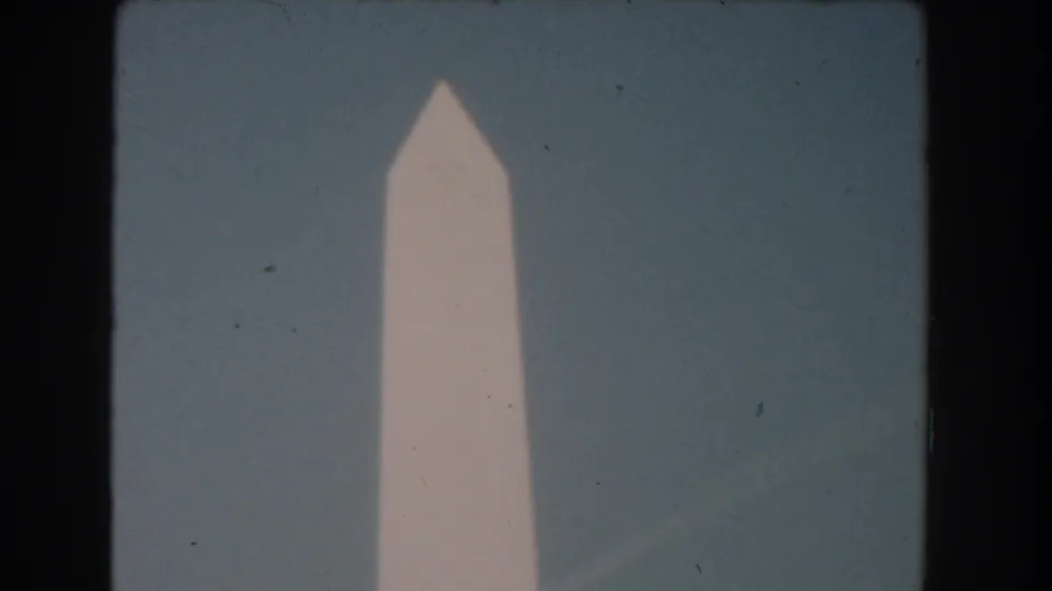 A slightly wider 1960 Washington DC frame shows the upper Washington Monument with blue sky and home-movie film texture.