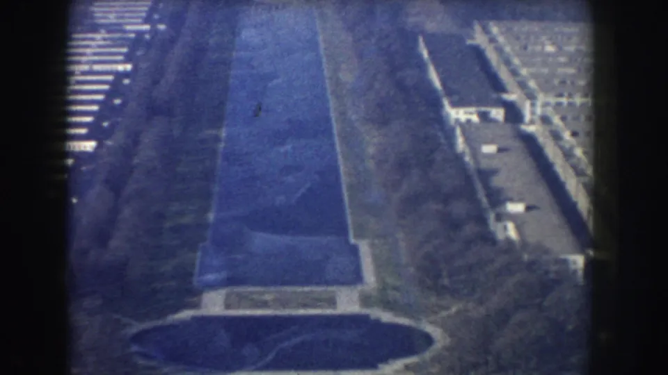 1960 aerial 8mm frame looking down the Reflecting Pool with roads, tree cover, and nearby Washington, DC buildings.
