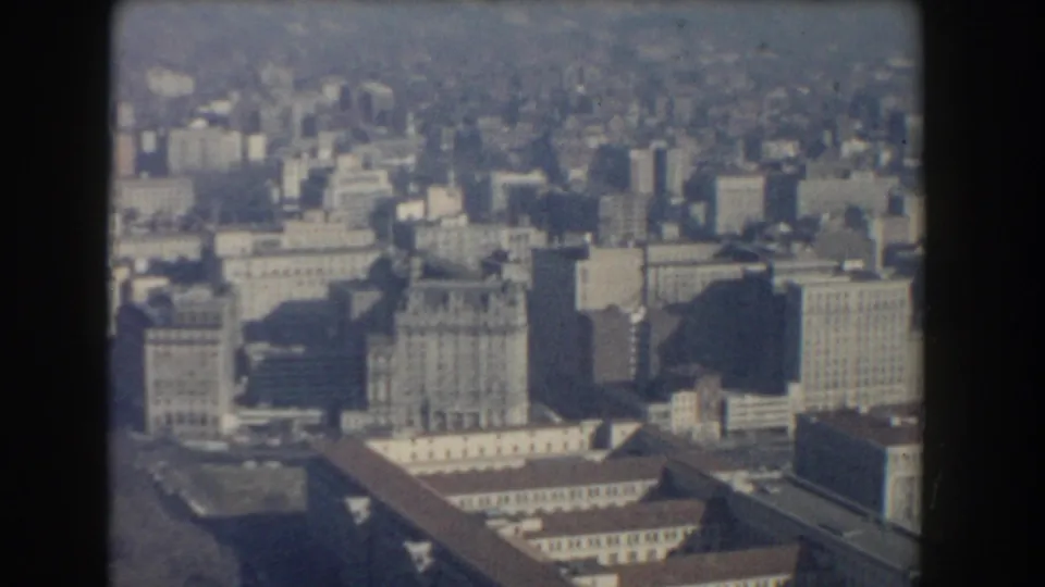 Washington, DC cityscape from a high vantage point, showing mid-century office towers, rooftops, and broad urban blocks.