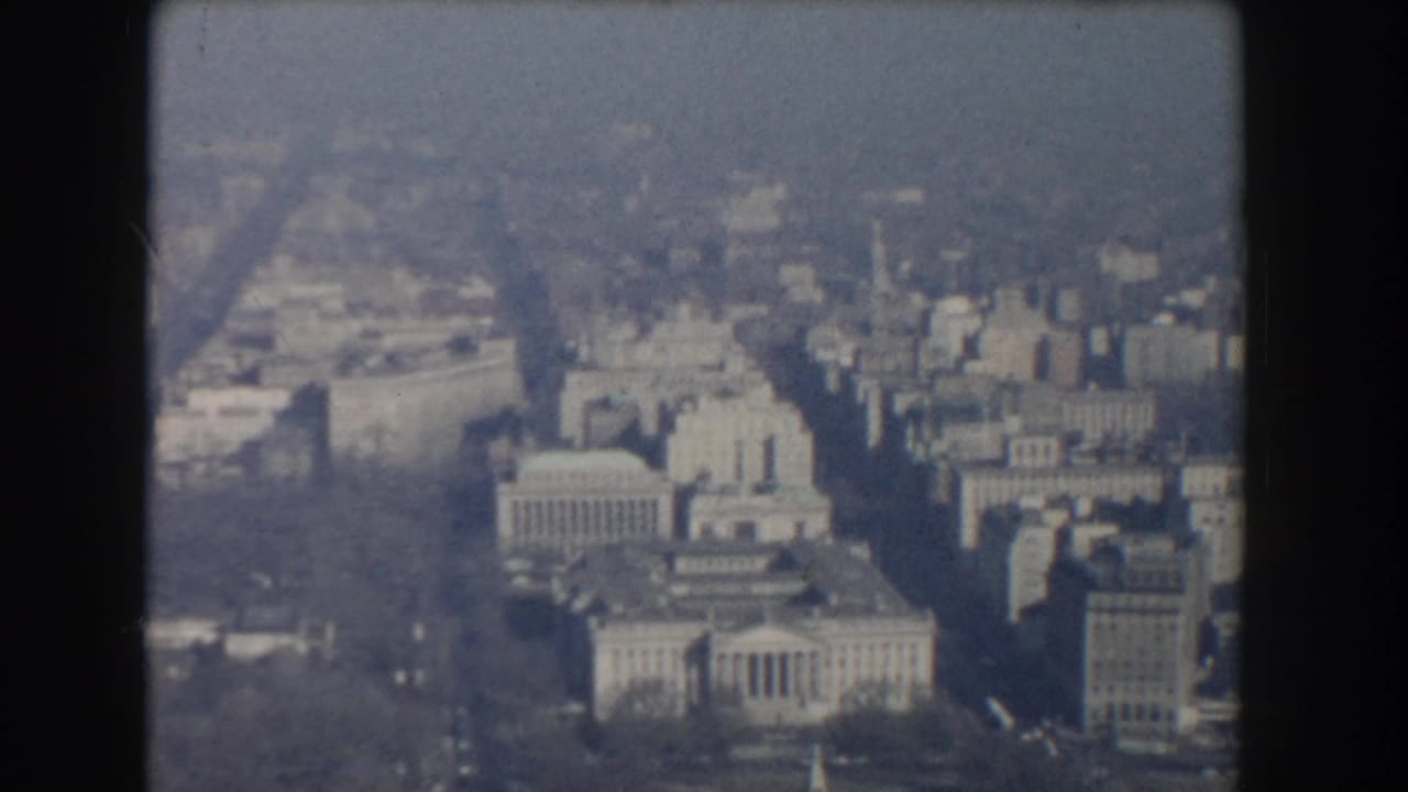 1960 aerial 8mm view over Washington, DC with neoclassical government buildings, streets, and soft haze.