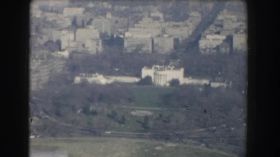 1960 Washington, DC aerial 8mm frame showing the White House grounds, green lawn, roadways, and surrounding urban blocks.