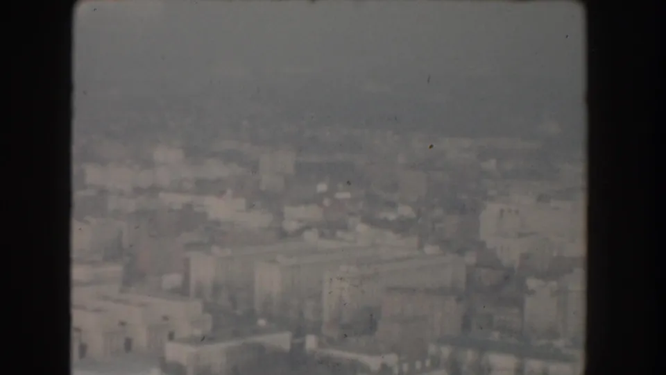 1960 Washington DC aerial view showing large institutional buildings, rooftops, streets, and a hazy urban background.