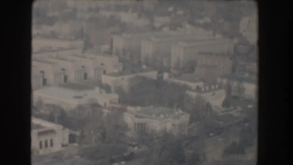 1960 Washington DC aerial frame showing government buildings, roads, winter trees, and a rounded building near the lower foreground.