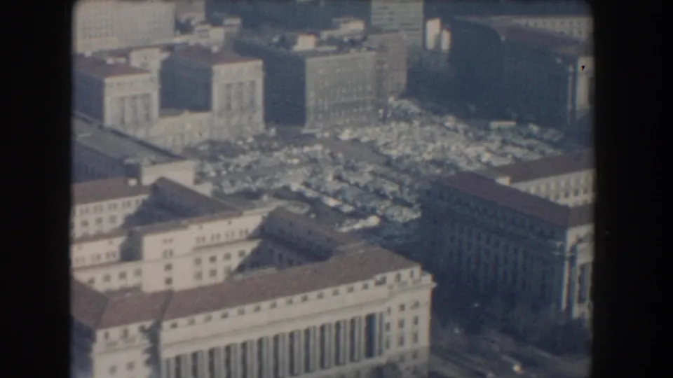 1960 Washington, DC aerial frame focused on a large classical building, adjacent parking lot, and urban blocks.