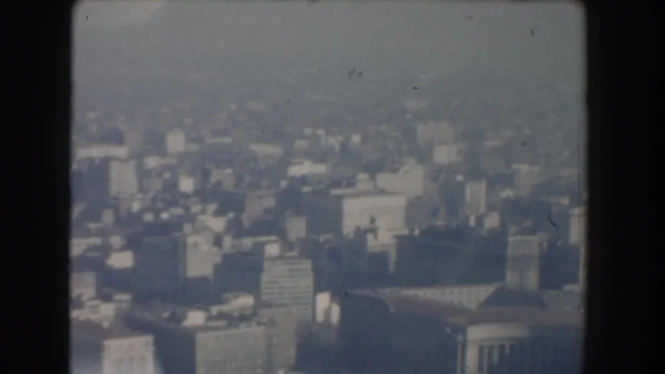 Hazy 1960 Washington, DC high-angle city view with distant buildings, soft focus, and visible 8mm frame edges.