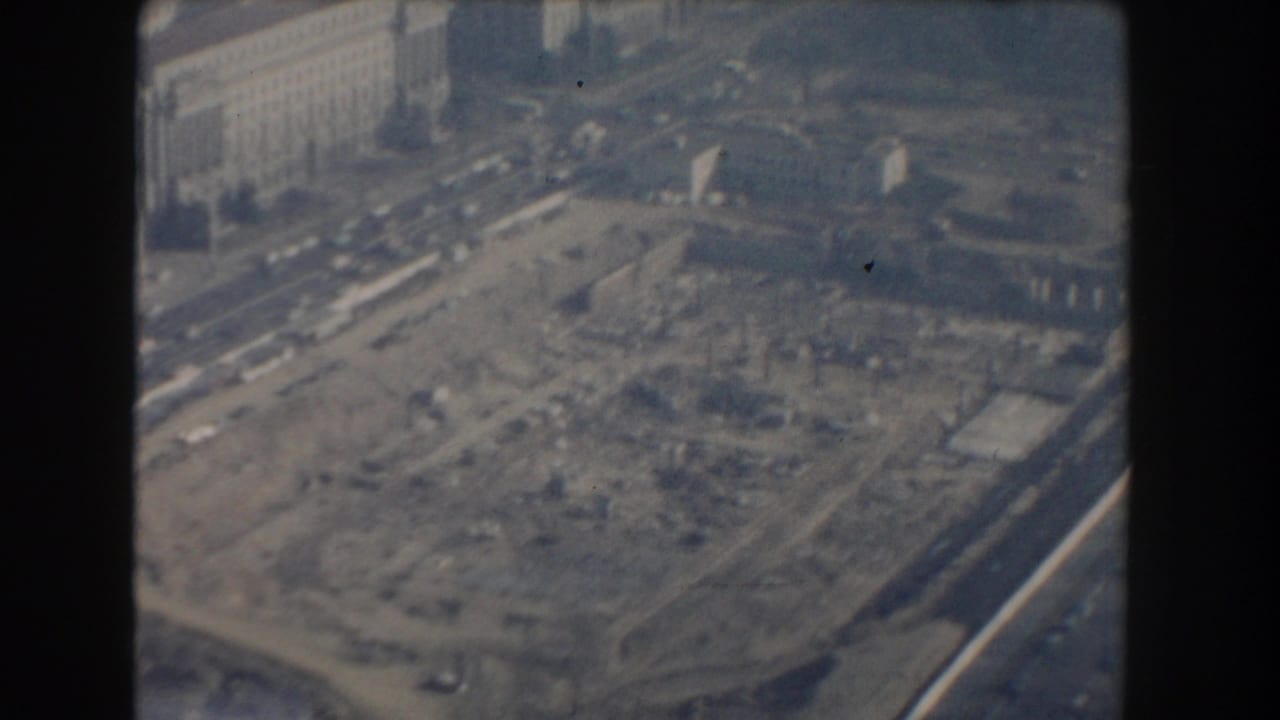 Elevated 1960 Washington, DC view of an excavated construction area with nearby roads, cars, and large masonry buildings.