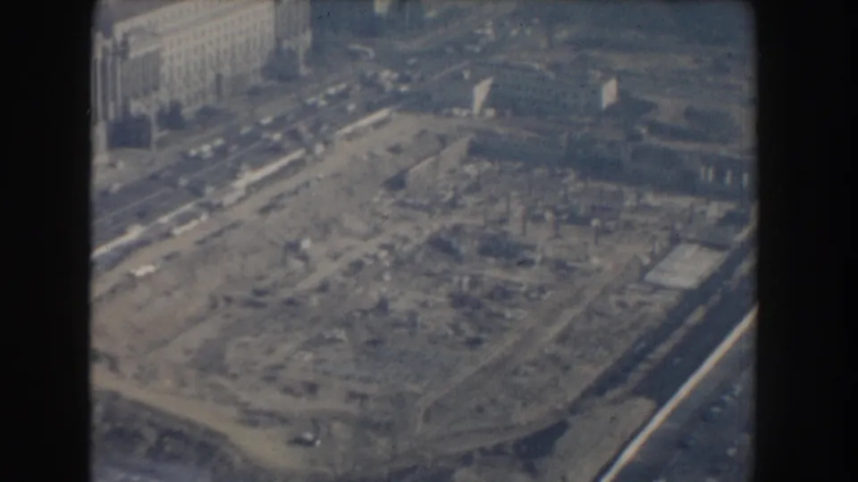 Grainy 1960 Washington, DC frame showing an elevated look over construction works, street traffic, and adjacent urban blocks.