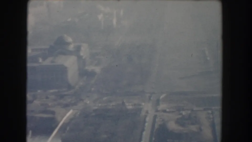 Hazy 1960 Washington, DC aerial view with a domed civic-style building, wide roadways, and muted urban background.