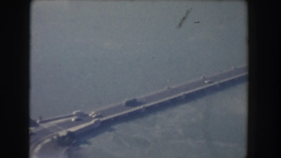 1960 Washington DC aerial frame with bridge traffic over a broad waterway, seen through soft 8mm focus.