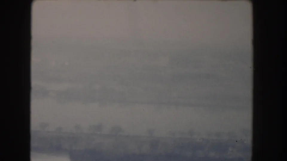 A hazy Washington DC exterior view on 8mm film, with a pale sky, distant forms, and dark frame edging.