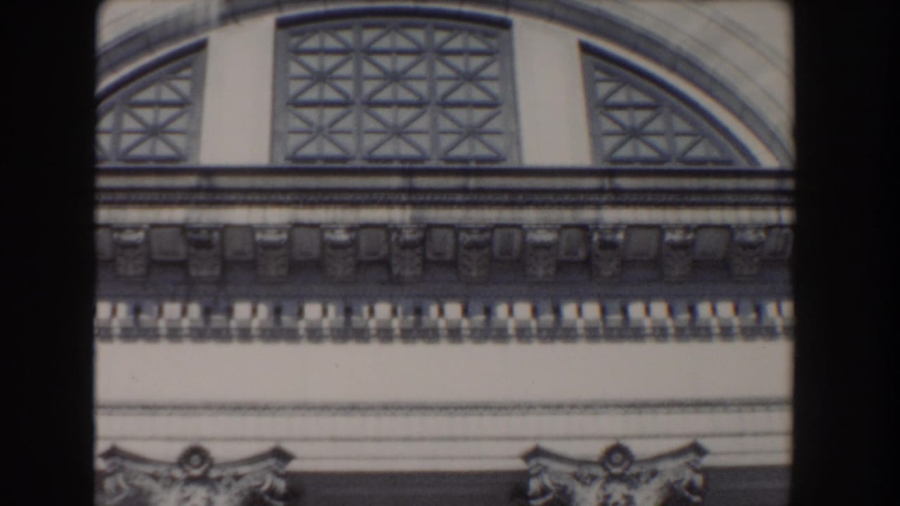 Ornate arched window and decorative stonework on a classical building facade.