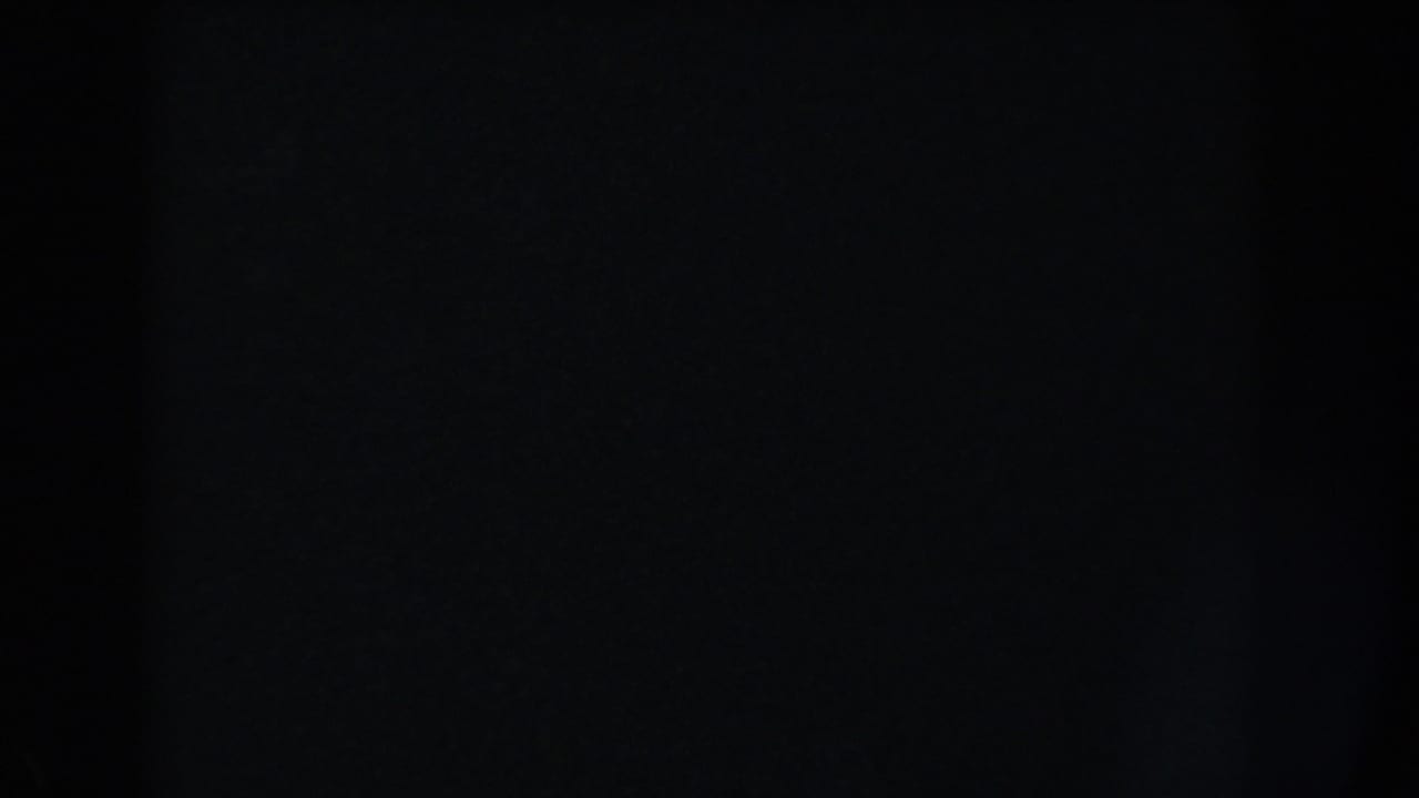 Dark frame with faint film grain and no discernible shapes.
