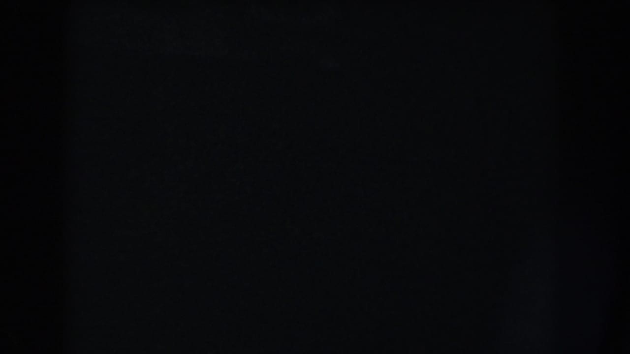 Nearly black frame with faint film grain and a dark vertical band.