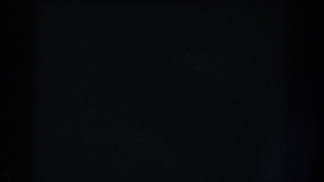 Dark frame with a faint central vertical shadow and minimal visible detail.